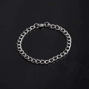 Close-up of a silver gear shift pendant on a link chain bracelet with a reflective black base
