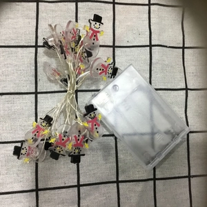 Close-up of snowman-shaped LED string lights with battery box on a checkered cloth