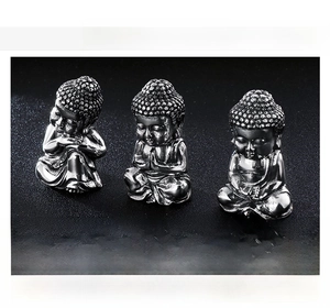 Detailed view of three mini stainless steel Buddha statues in different Zen poses