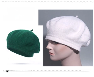 Detail of wool blend beret hats in dark green and white showing soft knit texture