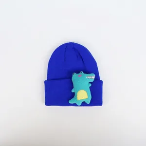 Detail einer königsblauen Strickmütze mit grüner 3D-Cartoon-Dinosaurier-Stickerei
