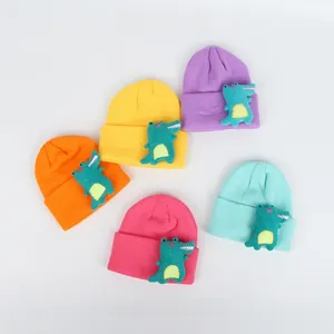 Detail view of five candy-colored kids knit hats with cute green dinosaur doll patches