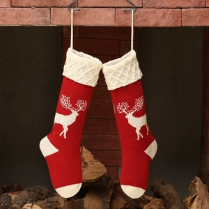 Red and white knitted Christmas stockings with reindeer patterns on brick fireplace
