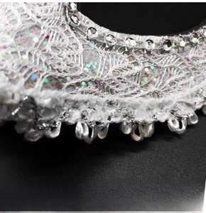 Macro detail of white lace masquerade mask with sparkling rhinestones and glitter