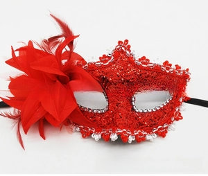 Macro detail of red lace masquerade mask with silk flowers and elegant red feathers