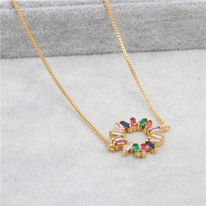 Detailed close-up of a gold necklace featuring a circular pendant with multi-colored zircons