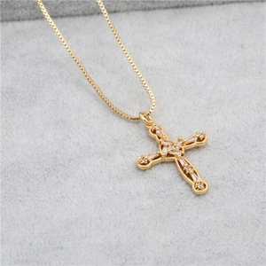 Close-up of a gold cross pendant necklace with micro-pave zircons on gray velvet background