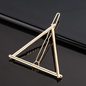 Barrette à cheveux triangulaire dorée minimaliste sur une surface miroir noire