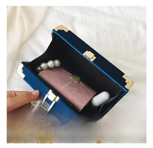 Internal capacity of the blue velvet box bag showing space for wallet and earbuds