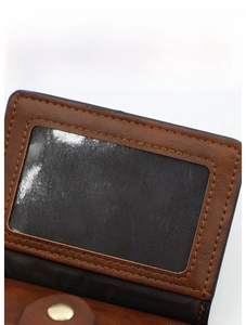 Detail of brown leather wallet featuring a transparent ID photo slot and metal snap button