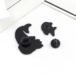 Detail view of black metal brooch backs with secure rubber clutches on white fabric