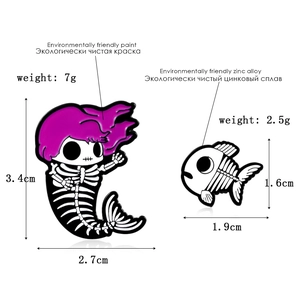 Detail view of mermaid and fish skeleton enamel pins with size and material specifications