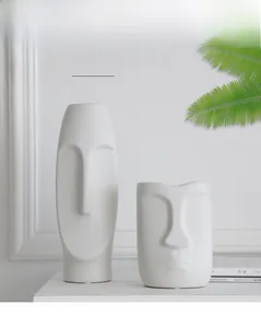 Close-up of abstract face relief on matte white ceramic vase in Nordic artistic style