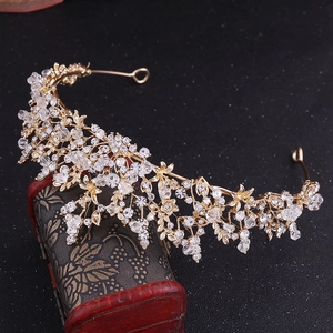 Detailed side view of golden bridal crown with crystal flower motifs on vintage wood box