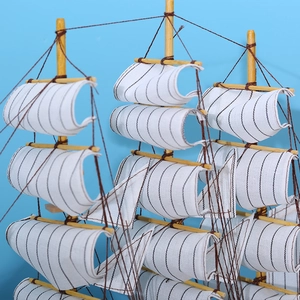 Maquette de voilier en bois avec voiles rayées blanches pour décoration de bureau