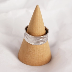 Macro shot of silver textured wide ring displayed on a wooden cone stand