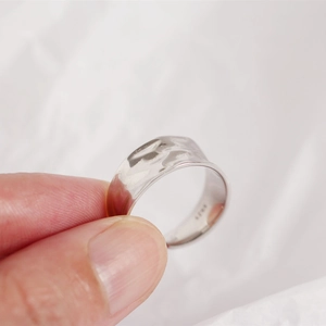 Detailed macro shot of irregular hammered texture on S925 sterling silver wide ring band