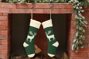 Knitted Christmas stockings with reindeer pattern hanging on a brick fireplace