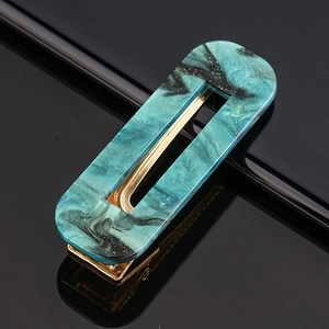 Macro detail of marble pattern acetate hair clip with teal textures and gold metal base