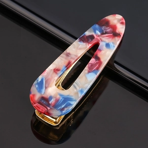 Macro view of colorful marble acetate hair clip with gold metal base on black background