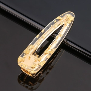 Detail of water drop acetate hair clip with gold foil flakes on black mirror background