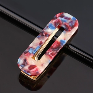 Detailed macro of marble texture acetate hair clip with golden metal base on black mirror