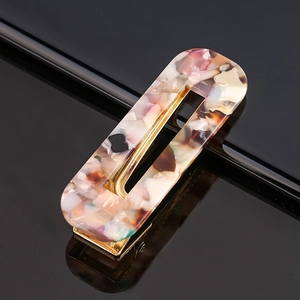 Macro detail of acetate hair clip with pink marble texture and gold metallic base