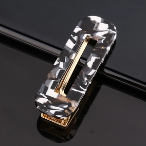 Detail view of a rectangular cutout acetate hair clip with black and white marble texture