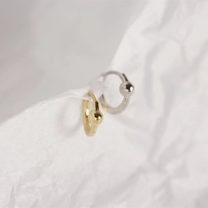 Macro shot of minimalist S925 sterling silver hoop earrings with gold and silver beads