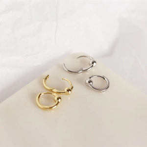 Macro detail of S925 sterling silver hoop earrings with bead accents in gold and silver
