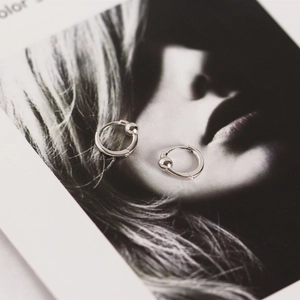 Detail of silver S925 geometric hoop earrings with small beads on an artistic card