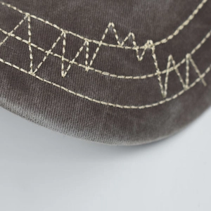 Macro shot of greyish-brown washed cotton fabric with detailed white contrast stitching detail