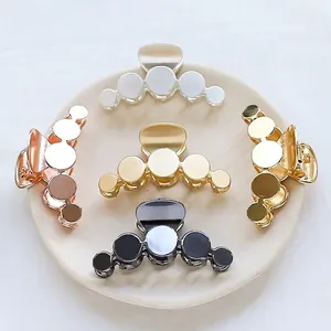 Minimalist geometric alloy hair claws in gold and silver finishes on a ceramic plate