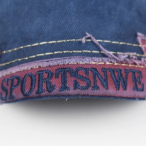 Close-up of navy denim embroidery detail with red logo tape and yellow contrast stitching