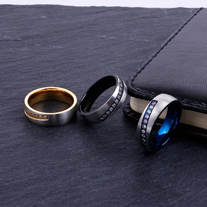 Three-piece men's brushed stainless steel rings with inlay stones on dark stone background