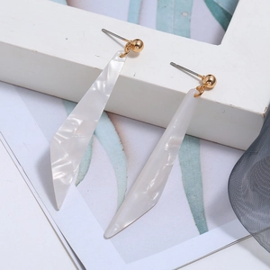 Detail of long white acrylic earrings with wavy texture and golden metal studs