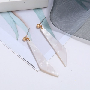 Detailed view of long triangular acetate earrings with white pearlescent texture and gold studs