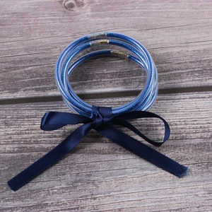 Close-up of glitter-filled blue silicone bangles with a satin ribbon bow on wood