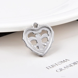 Macro shot of silver heart pendant with fleur-de-lis hollow design on white background