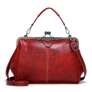 Detail of red vintage leather handbag showing metal frame clasp and textured pattern