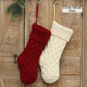 Detail of 37cm cable knit Christmas stockings in red and cream on a wooden door backdrop