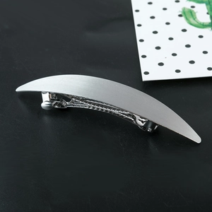Macro detail of curved silver metal hair clip with a professional brushed texture finish