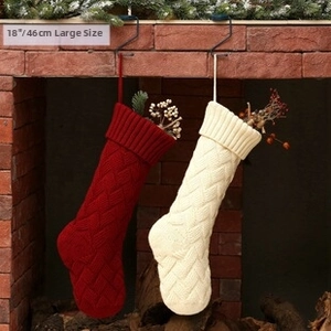 Detail of red and cream knitted Christmas stockings with berries on a brick fireplace
