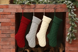 Set of four knitted Christmas stockings in festive colors hanging over a brick fireplace