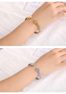 Detail of mesh stainless steel open bangles in gold and silver with bear charms