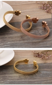 Close-up of gold and rose gold mesh bracelets with angel charms on dark wood