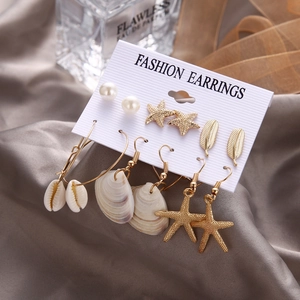 6-pair set of ocean-themed earrings featuring gold starfish shells and pearls on white card