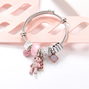 Pink bear charm bracelet with stainless steel beads and engraved heart on white surface