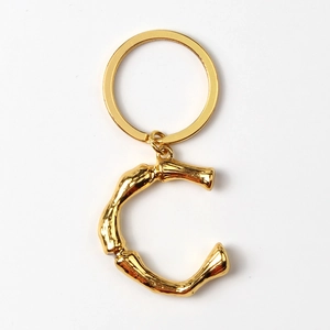 Macro detail of a golden metal letter C keychain with a polished shiny gold keyring
