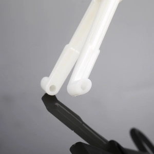 Close-up of white L-shaped plastic piercing tool ends with hollow circular openings